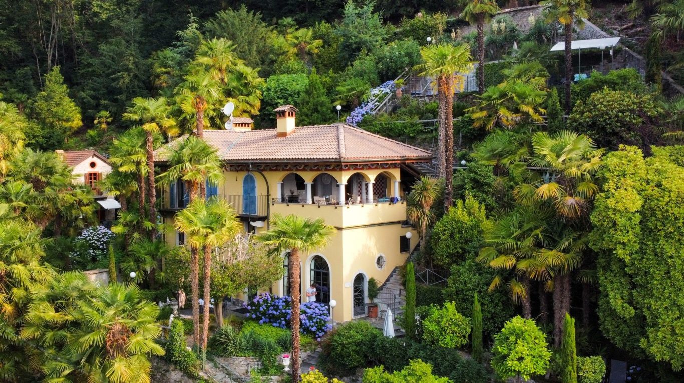 Villa Zanotti und Rustico Orponte. Das Bild zeigt die Villa Zanotti und das Rustico Orponte in ihrem Garten voller Palmen.
